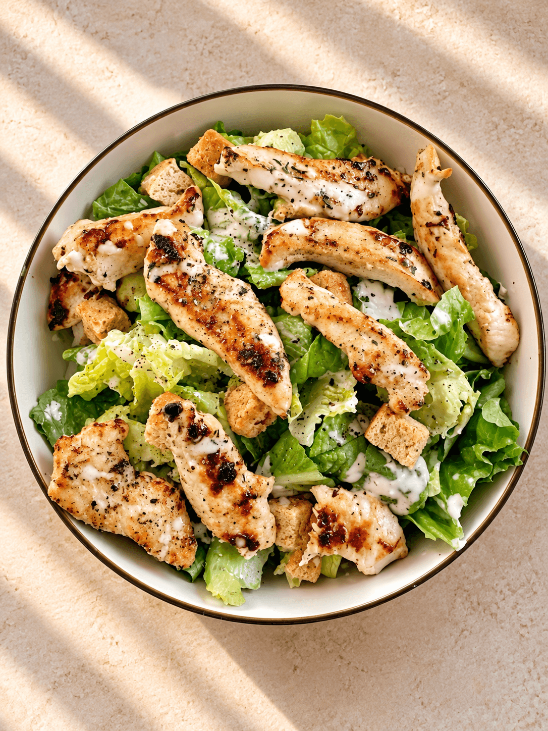 Grilled chicken Caesar salad in a white bowl